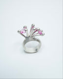 Silver ring with pink gemstones on a white background