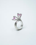 Silver ring with pink gemstones on a white background