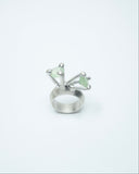 Silver ring with green gemstones on a white background