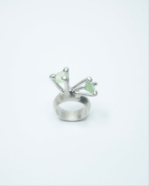 Silver ring with green gemstones on a white background